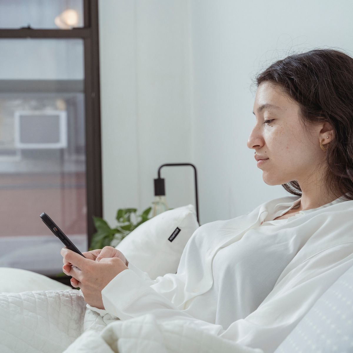 Calm woman using her smartphone to tap a book a session button on a therapy website
